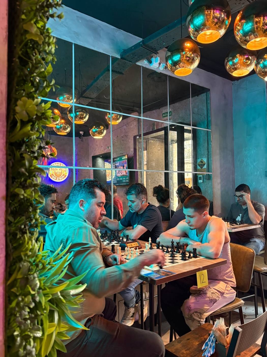 Mesas de juego junto a la pared vegetal del bar